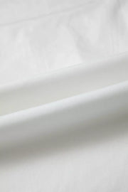 White cotton shirt with subtle pleating and ruffled details.