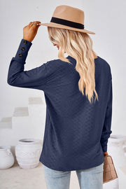 Dark blue textured V-neck blouse with button cuff detail.
