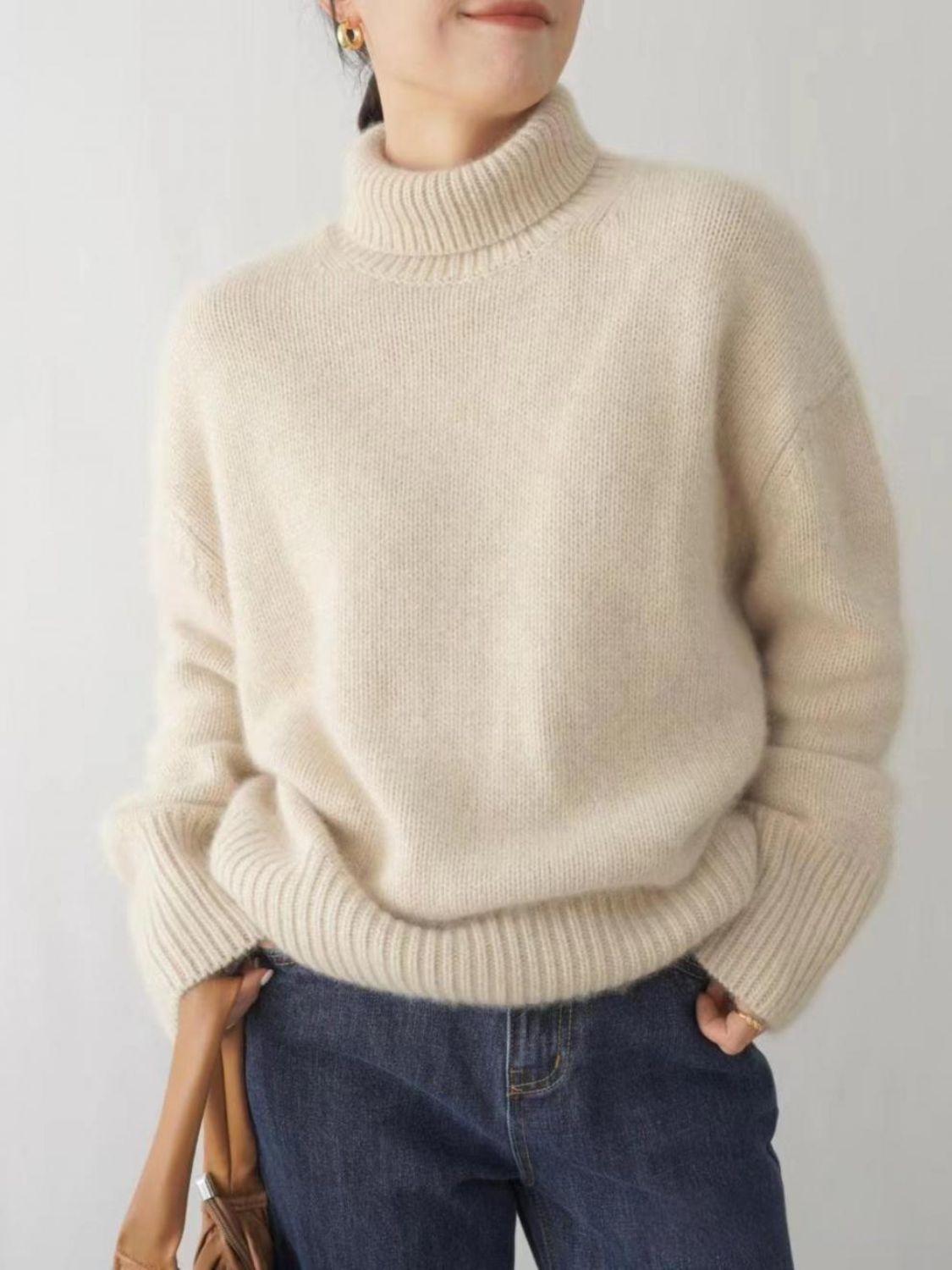 Cream cashmere turtleneck sweater with relaxed fit and ribbed cuffs and hem.