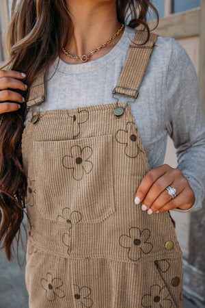 Khaki corduroy overalls with a relaxed fit and floral pattern, featuring a bib pocket.