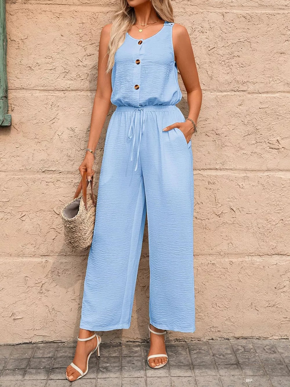 Sky blue wide-leg romper with button detail, drawstring waist, and textured fabric.