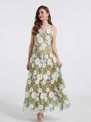 Embroidered floral maxi dress with appliqué in green, featuring white and blue flowers, spaghetti straps, and a full skirt.