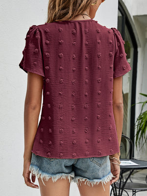 Textured puff sleeve wine blouse with dot pattern and V-neck, styled with denim shorts.