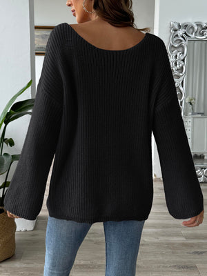 Black knit sweater with wide neckline and balloon sleeves, styled with jeans.
