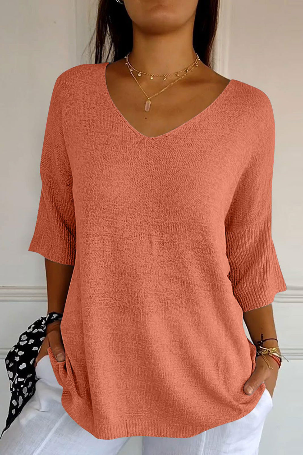 Orange V-neck knit sweater with flared sleeves and textured fabric.