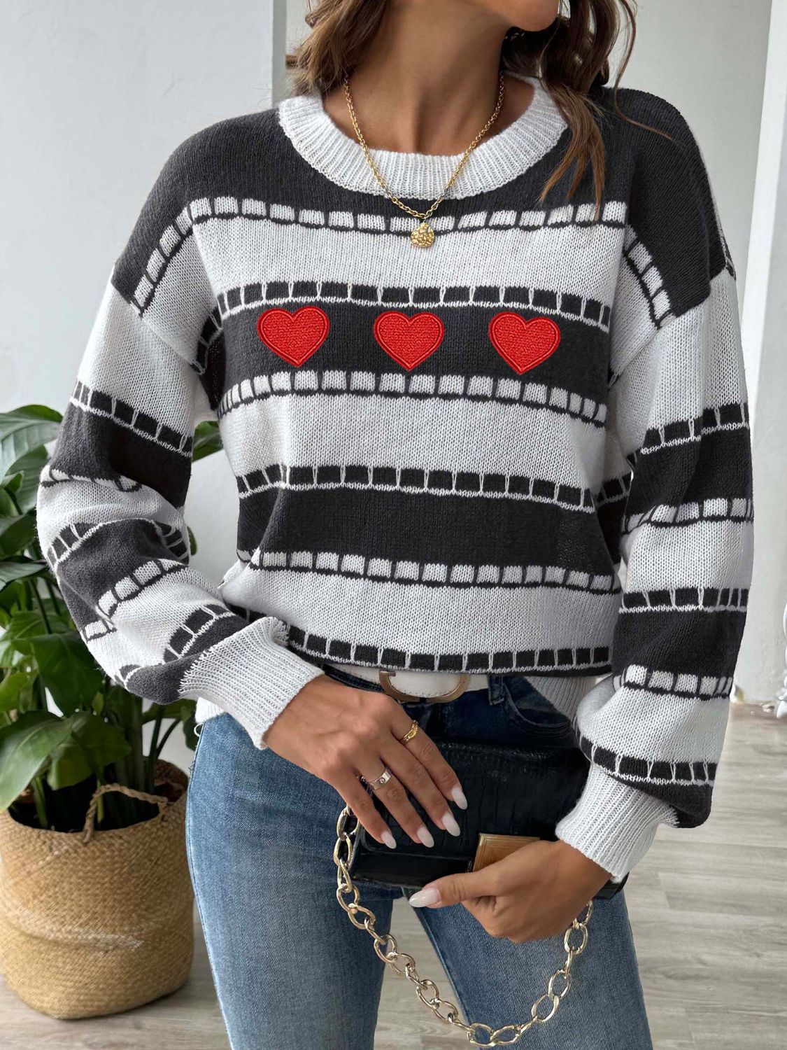 Black and white striped knit sweater with embroidered red hearts, crew neck, long sleeves.