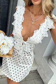 White polka dot mini dress with lace trim and tie front.