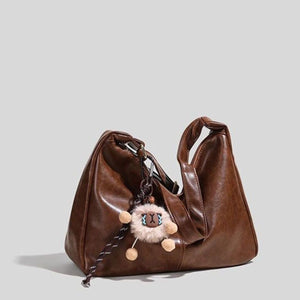 Brown vintage hobo shoulder bag with fluffy sheep charm and braided strap detail.