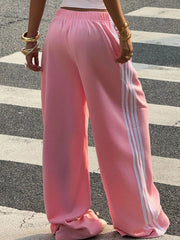 Pink wide leg sweatpants with white side stripes and elastic waistband.