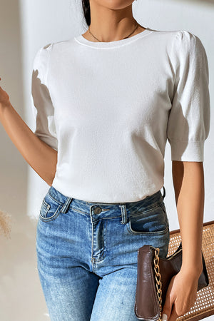 White knit sweater with puff sleeves and crew neck, styled with jeans.