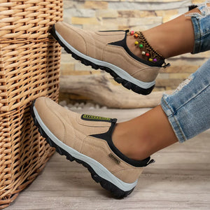 Khaki suede-like round toe slip-on sneakers with black trim and a colorful beaded anklet.