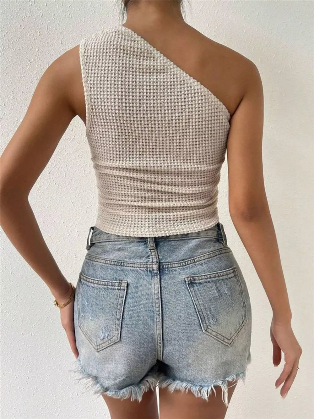 Asymmetrical waffle knit tank top in apricot, one-shoulder design.