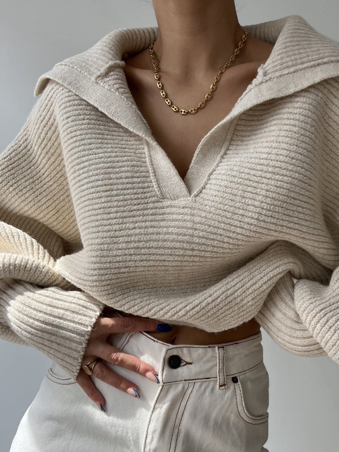 Cream knit sweater with wide collar and balloon sleeves, styled with white jeans.