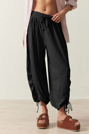 Black gathered ankle-tie balloon trousers with drawstring waist and cuffs.