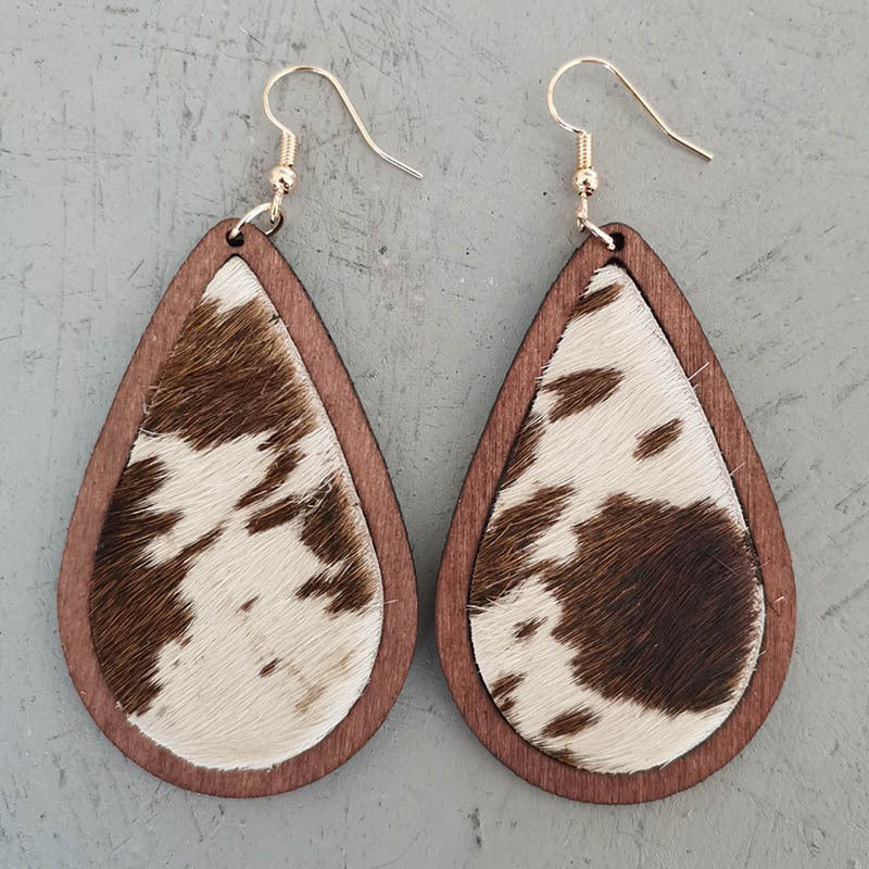 Teardrop wood earrings with cowhide pattern in brown and white, featuring gold hooks.