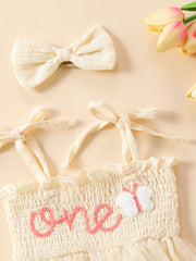 Apricot smocked baby bodysuit with pink "one" embroidery and butterfly detail, with matching bow headband.