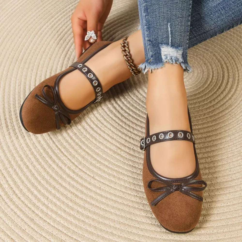 Brown Mary Jane flats with bow detail and adjustable strap with grommets.
