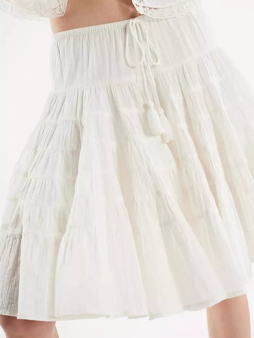 Tiered drawstring mini skirt in white with tassel detail.