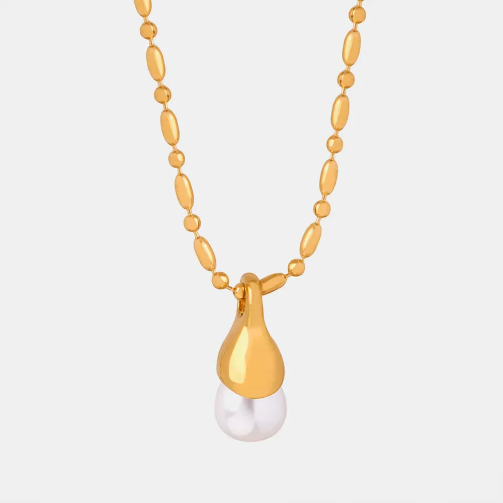 Gold necklace with oval beads and a teardrop pendant holding a pearl.