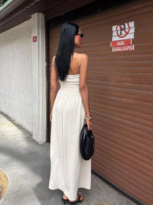 Beige smocked bodice relaxed maxi dress with strapless neckline and wide skirt.