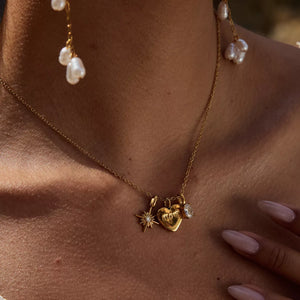 Gold charm necklace with heart, starburst, and crystal pendant.