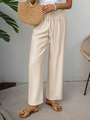 Chic tan waist-tie flare trousers with a relaxed fit and textured fabric.