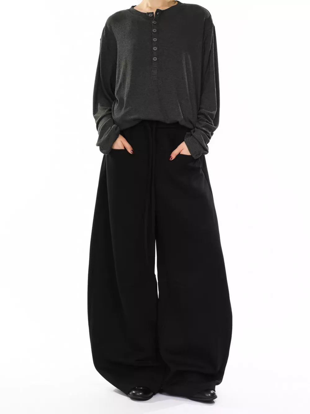 Black wide-leg sweatpants with drawstring and pockets, worn by a person in a gray long-sleeve shirt.