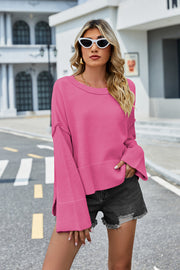Hot Pink acrylic knit sweater with flared sleeves and slit hem detail.