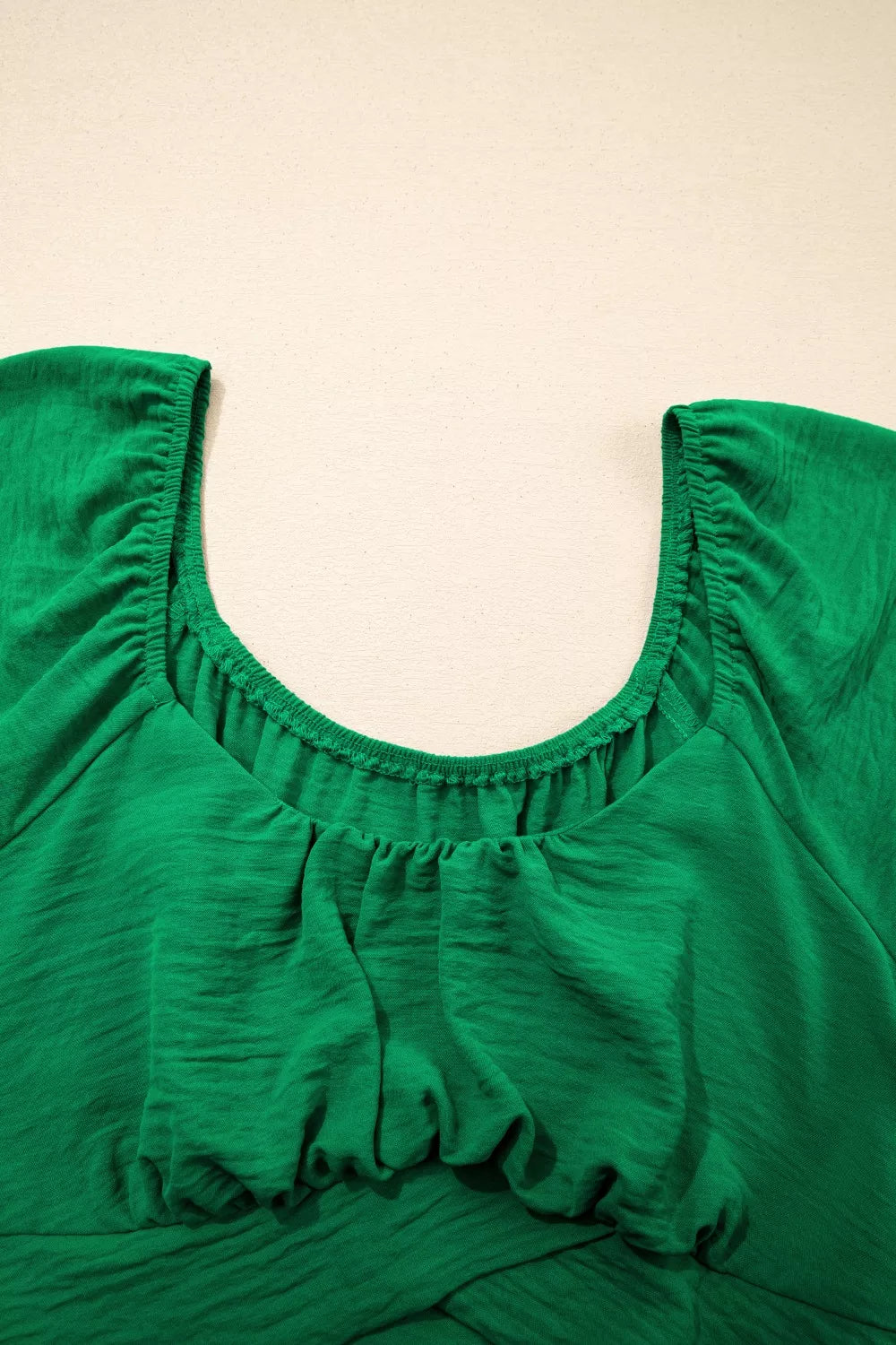 Green ruched polyester maternity shirt with crossed waist detail and gathered neckline.