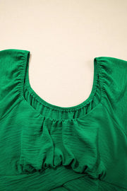Green ruched polyester maternity shirt with crossed waist detail and gathered neckline.