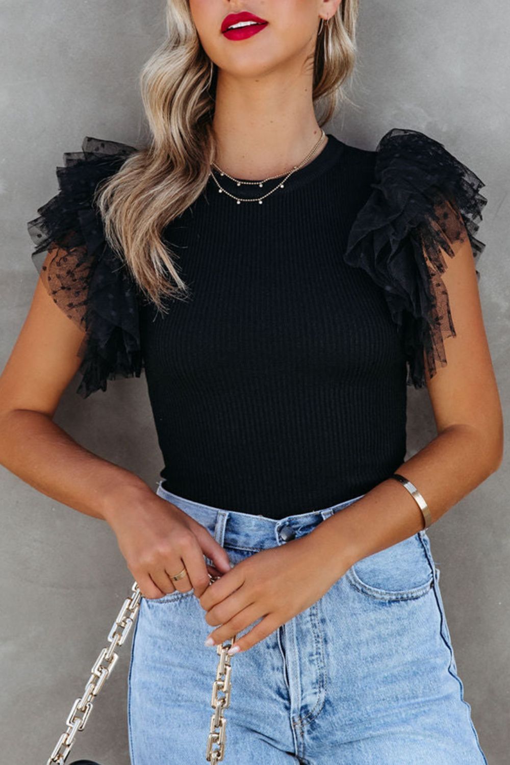 Black ribbed knit blouse with sheer polka dot ruffle sleeves