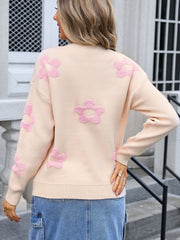 Apricot crewneck knit sweater with pink floral appliqués and long sleeves.