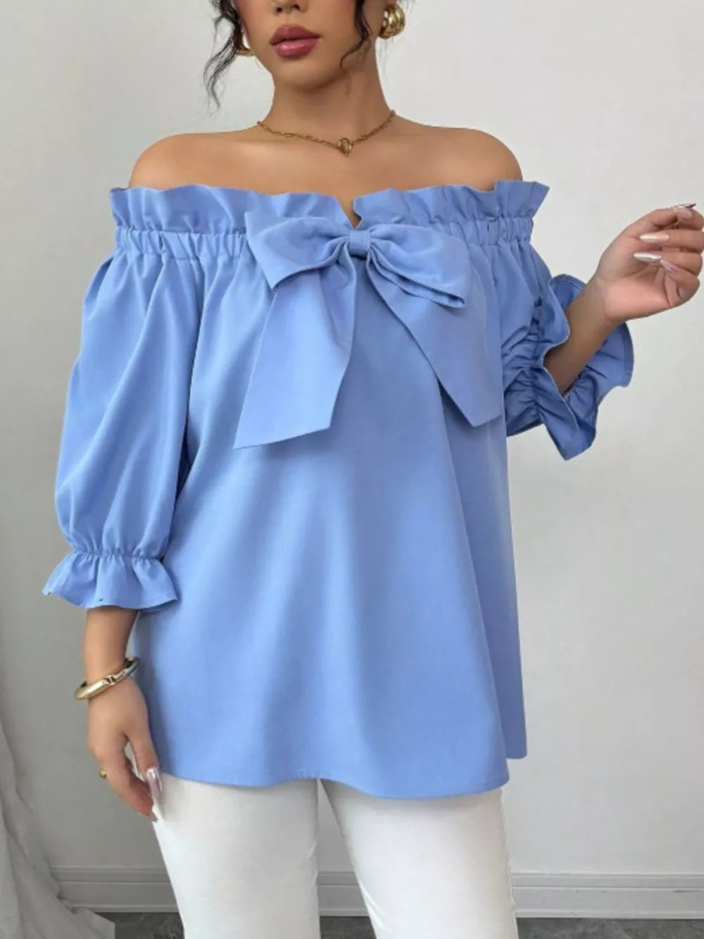 Sky blue off-the-shoulder blouse with ruffled neckline, bow detail, and ruffled sleeves.