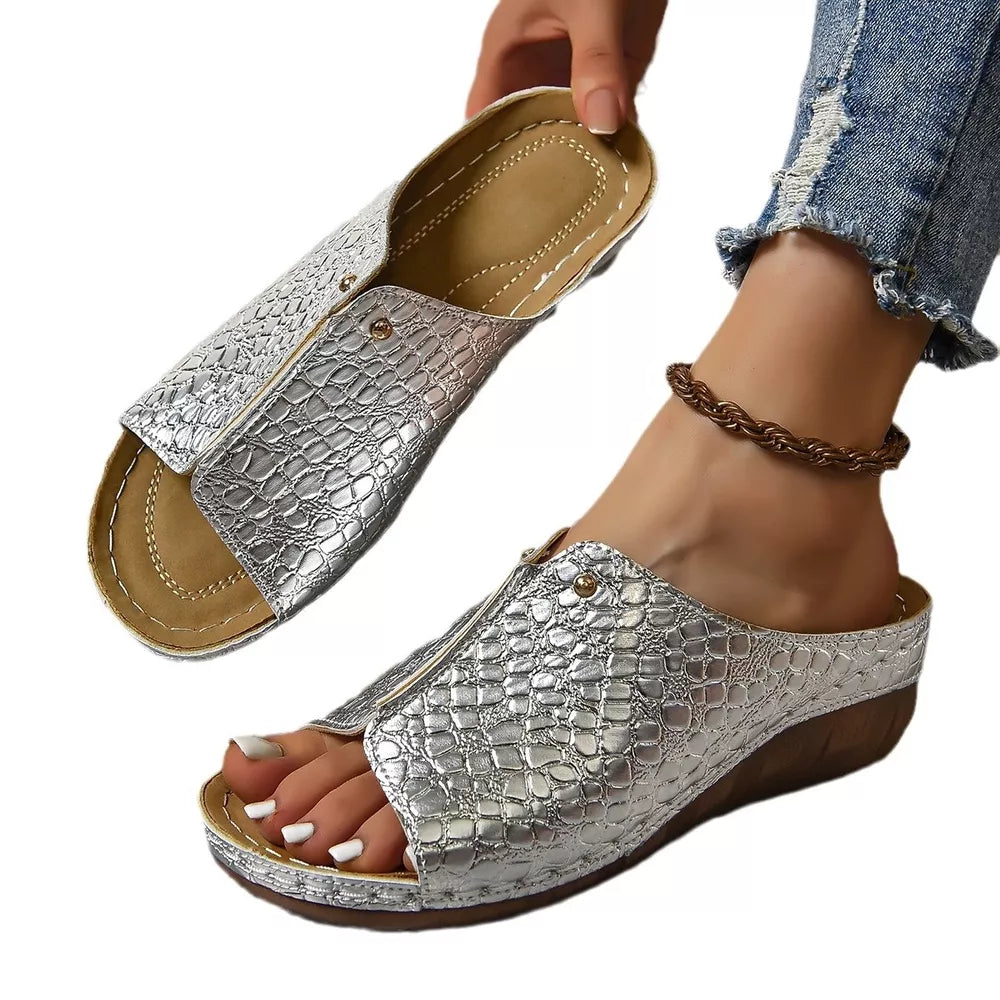 Silver glossy crocodile-embossed wedge sandals with open toe and zipper detail.