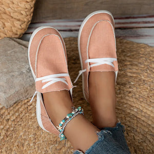 Coral canvas boat shoes with white contrast stitching and laces.