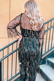 Black sequin duster with flared sleeves and fringe detail, worn over black pants.