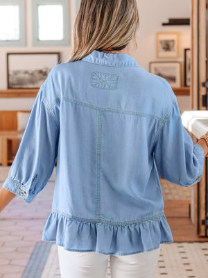 Light blue chambray button-down shirt with ruffled hem and 3/4 sleeves.