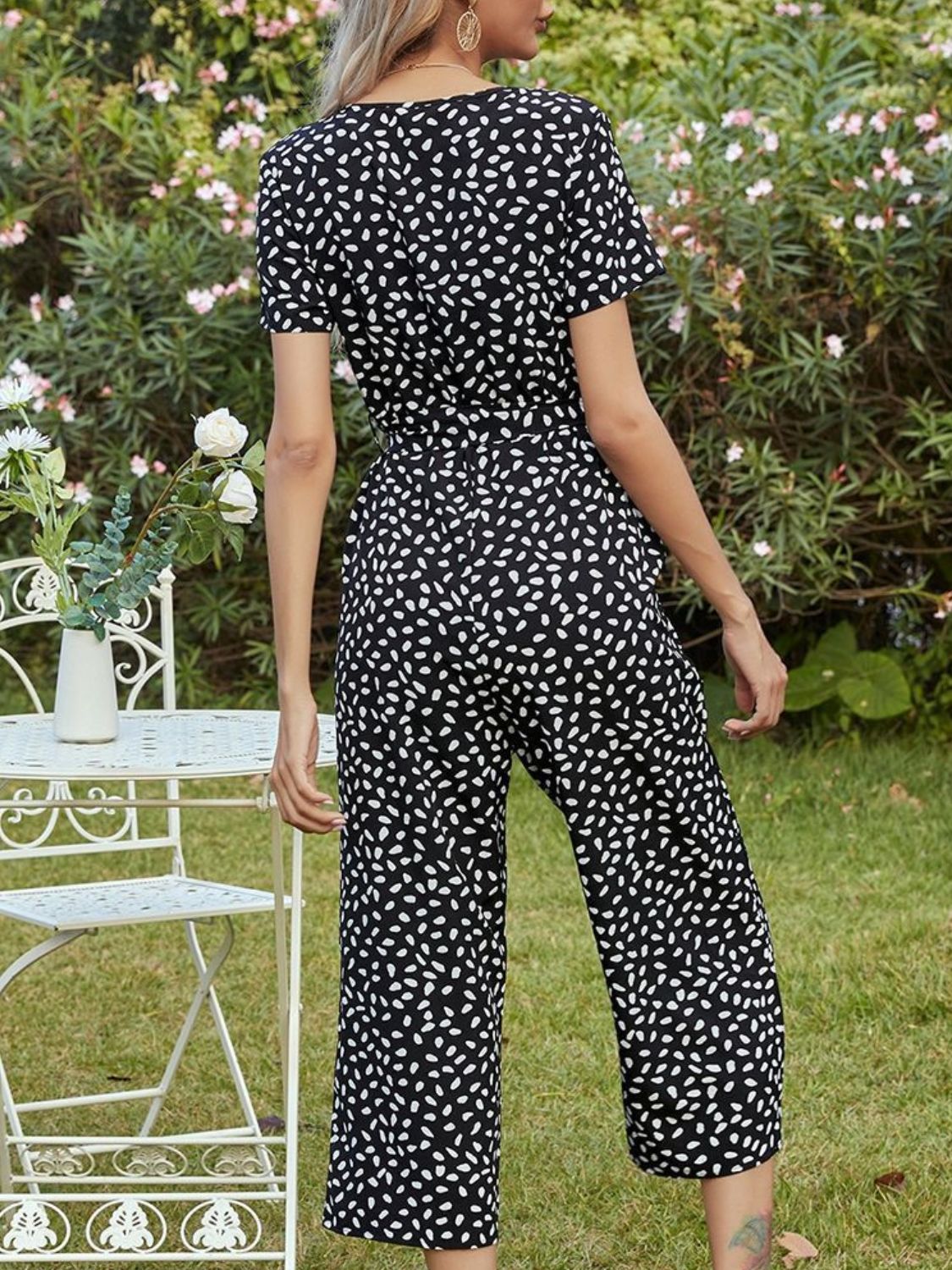Black dotted print button-down jumpsuit with tie waist and short sleeves