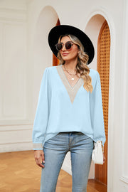 Mint blue blouson top with V-neck and embroidered trim detail.
