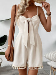 Beige textured romper with bow front, cutout, and tassel hem.