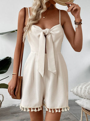 Beige textured romper with bow front, cutout, and tassel hem.