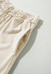 Beige wide-leg drawstring trousers with elastic waistband and side pocket detail.
