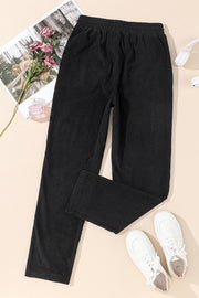 Black corduroy drawstring trousers with a relaxed fit and visible ribbing.