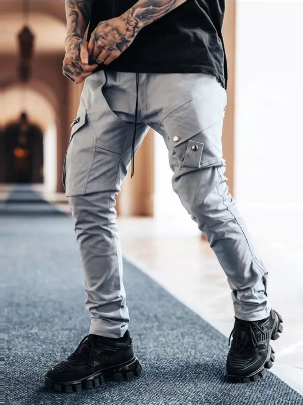 Gray zip pocket slim cargo trousers with snap-button flap pockets and drawstring waist.