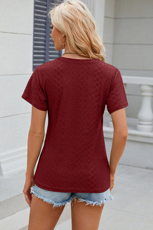 Burgundy eyelet wrap v-neck top with short sleeves and a textured pattern.