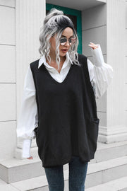 Black oversized knit vest with V-neck and pockets, styled over a white shirt.