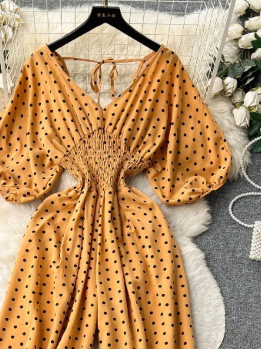 Yellow polka dot smocked wide-leg romper with V-neck and tie detail