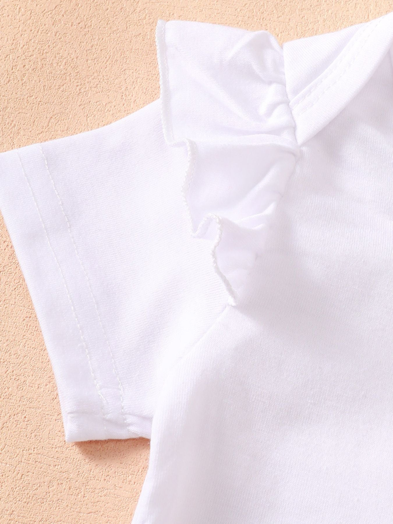 White cotton bodysuit with ruffled short sleeves and neckline detail.