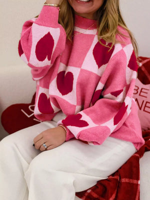 Pink knit sweater with heart checkerboard pattern and mock neck.