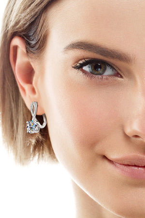 Silver crossover huggie earrings with a round moissanite stone.